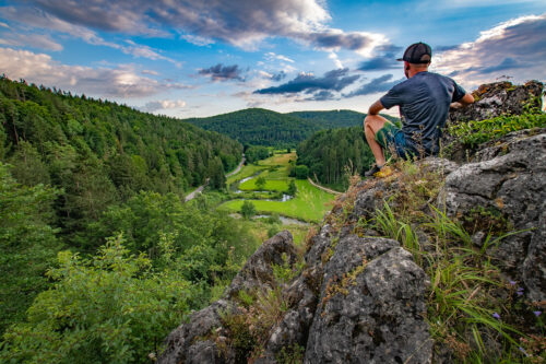 Wanderer sitz auf Fels und blickt ins Tal
